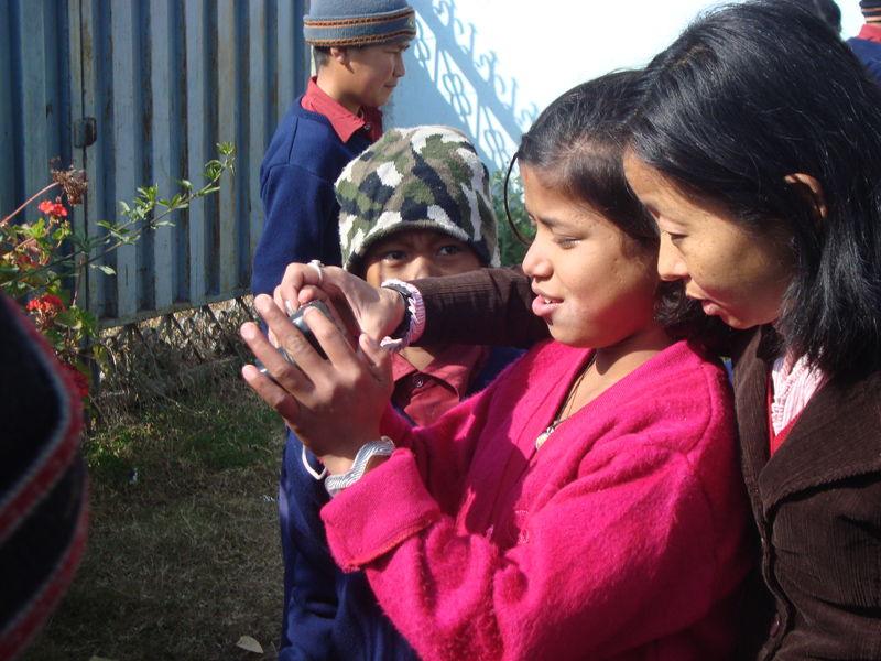 Children learning to operate digital camera
